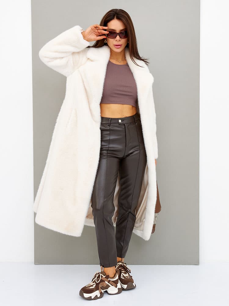 Девушка в белой шубе и очках смотрит прямо